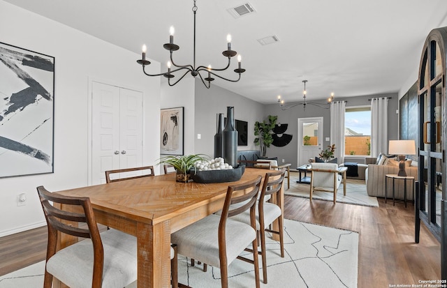 dining area featuring wood finished floors, visible vents, baseboards, and an inviting chandelier