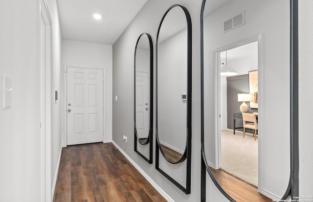 hall featuring dark wood-type flooring, visible vents, and baseboards