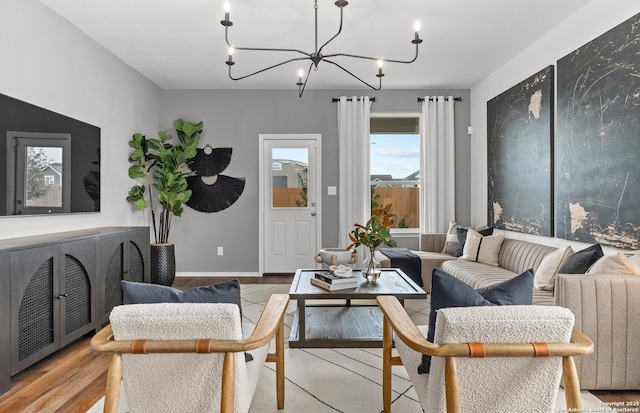 living room featuring light wood-style floors, a chandelier, and baseboards