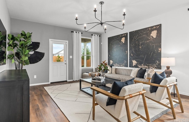 living area featuring an inviting chandelier, baseboards, and wood finished floors