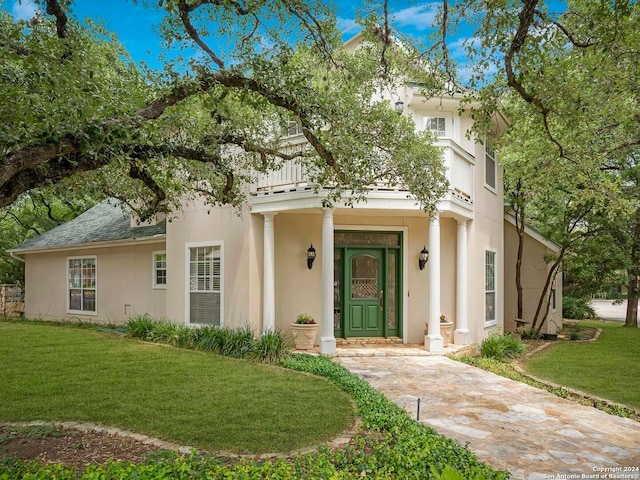 view of front of house with a front lawn, a shingled roof, and stucco siding