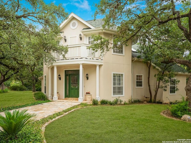 mediterranean / spanish home featuring a balcony, stucco siding, roof with shingles, and a front yard