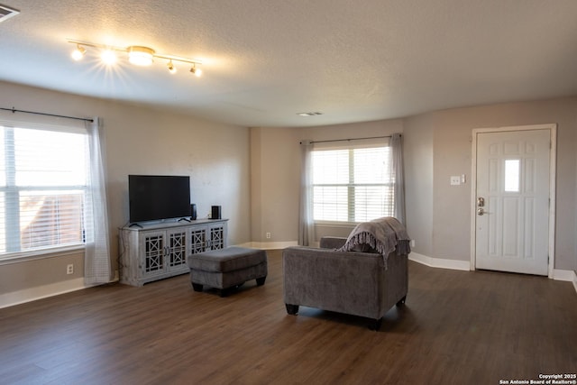 living area with dark wood-style floors, a textured ceiling, visible vents, and baseboards