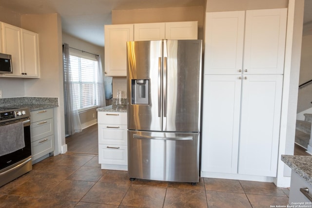 kitchen with appliances with stainless steel finishes, white cabinets, baseboards, and light stone countertops