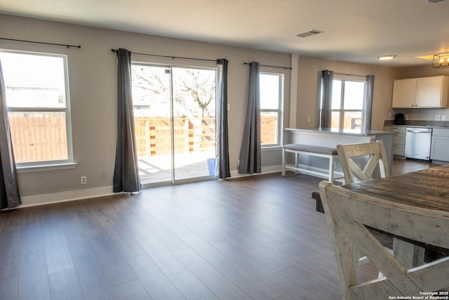 interior space featuring dark wood-style floors, visible vents, stainless steel dishwasher, white cabinets, and baseboards