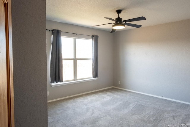 carpeted empty room with ceiling fan, a textured wall, a textured ceiling, and baseboards