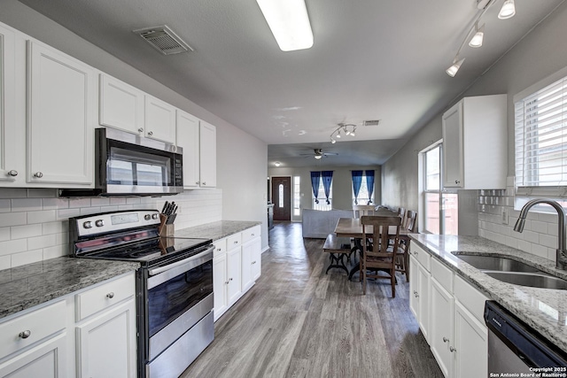 kitchen with stainless steel appliances, a sink, visible vents, white cabinets, and light wood-type flooring