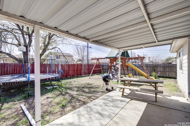 view of patio with a trampoline, a playground, and a fenced backyard