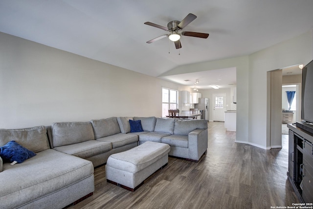 living room with dark wood-type flooring, vaulted ceiling, baseboards, and a ceiling fan