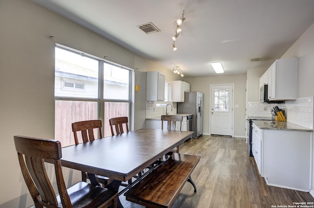 dining room with wood finished floors, visible vents, and baseboards