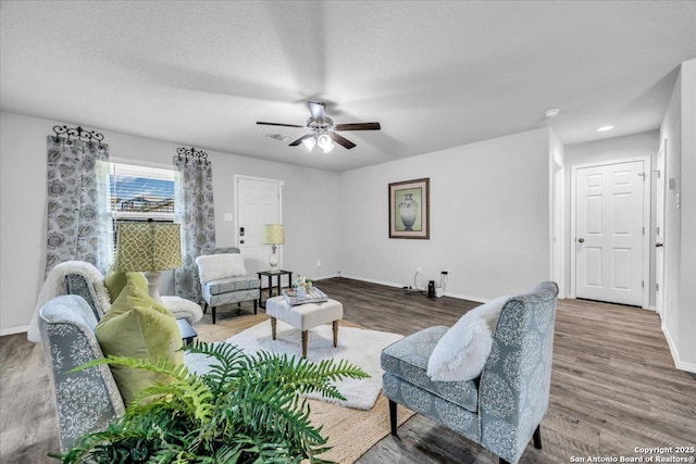 living room with a ceiling fan, baseboards, and wood finished floors