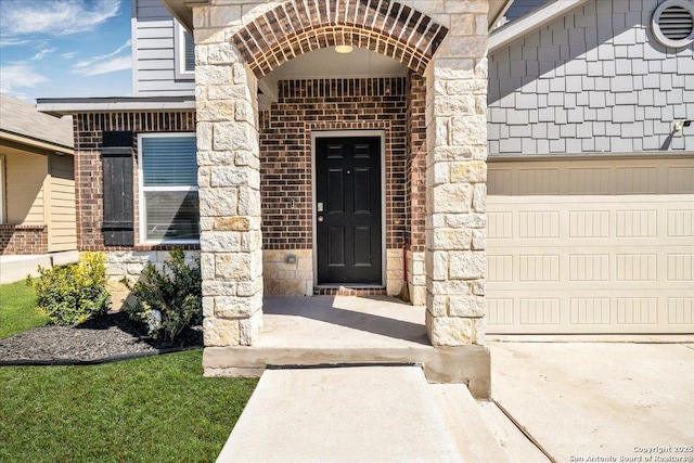 view of exterior entry featuring a garage, stone siding, and brick siding