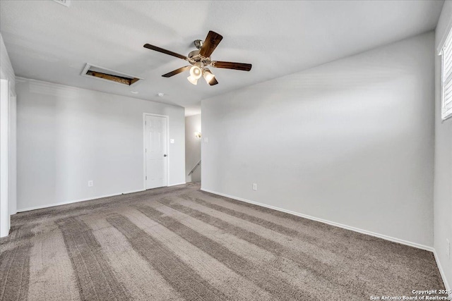 unfurnished room featuring carpet floors, attic access, baseboards, and a ceiling fan