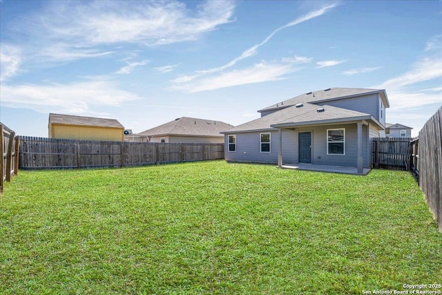 rear view of house with a lawn and a fenced backyard