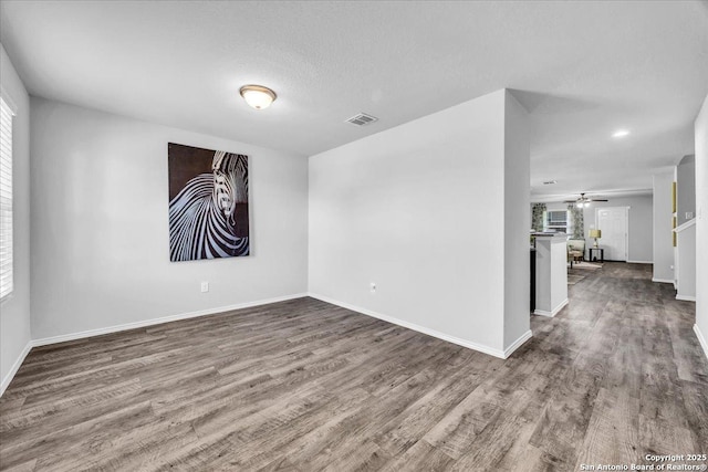 spare room with visible vents, ceiling fan, a textured ceiling, wood finished floors, and baseboards