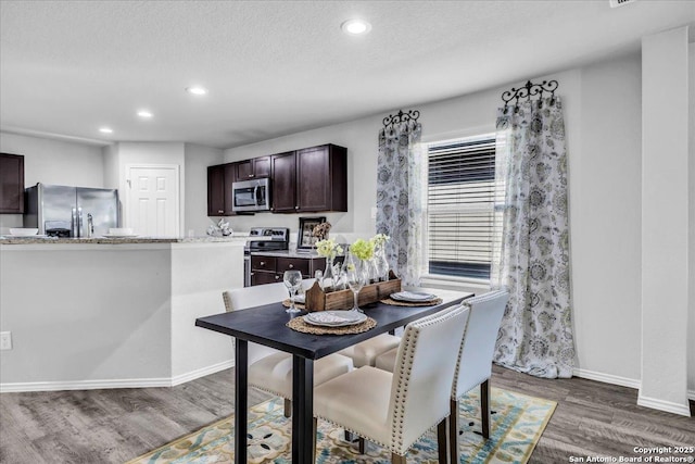 dining room with recessed lighting, a textured ceiling, baseboards, and wood finished floors