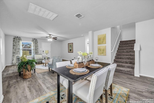 dining room featuring visible vents, baseboards, a ceiling fan, stairway, and wood finished floors