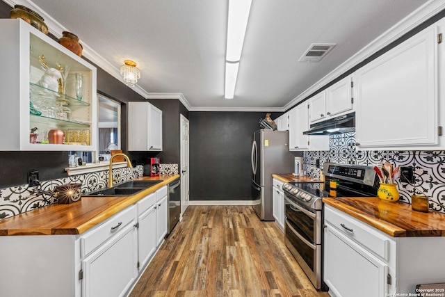 kitchen with visible vents, appliances with stainless steel finishes, a sink, wood counters, and under cabinet range hood