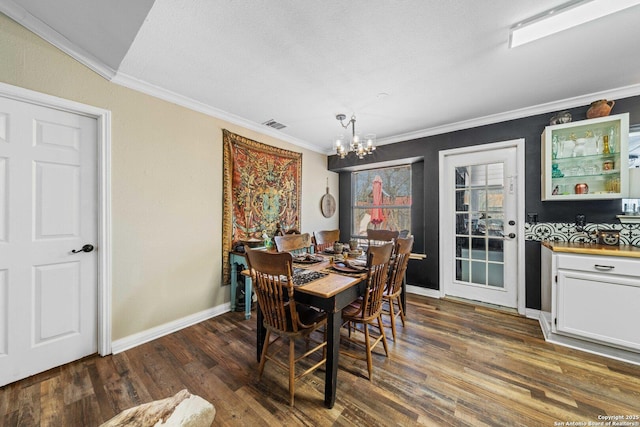 dining space with baseboards, visible vents, dark wood finished floors, ornamental molding, and a notable chandelier