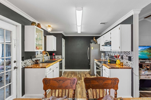 kitchen featuring wooden counters, appliances with stainless steel finishes, white cabinets, a sink, and under cabinet range hood