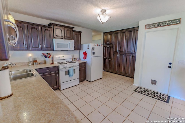 kitchen with white appliances, light countertops, a sink, and dark brown cabinetry