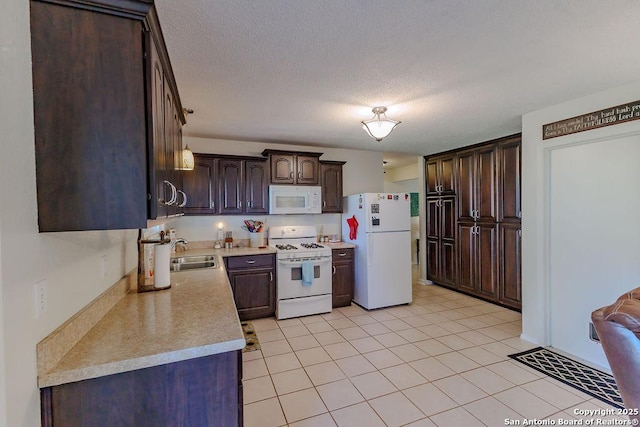 kitchen with a textured ceiling, white appliances, a sink, dark brown cabinets, and light countertops