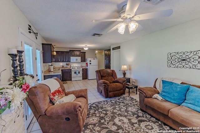 living area with light tile patterned floors, ceiling fan, a textured ceiling, and visible vents