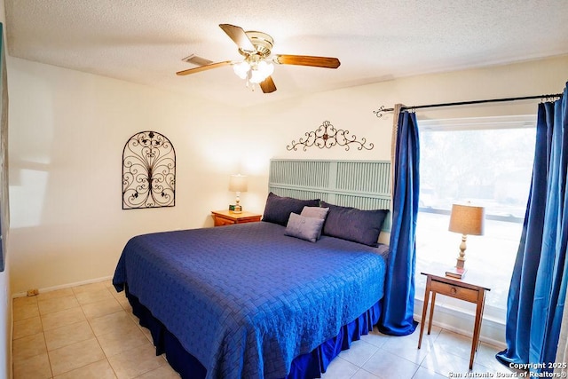 bedroom featuring a ceiling fan, a textured ceiling, and light tile patterned floors