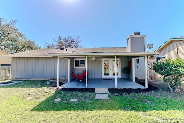 back of property featuring fence, a yard, board and batten siding, a chimney, and a patio area