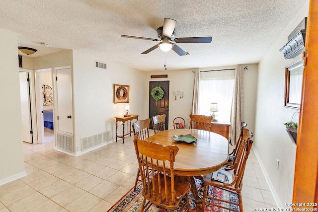 dining room with light tile patterned floors, a textured ceiling, visible vents, and baseboards