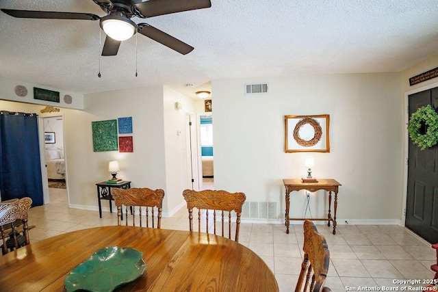 dining area featuring light tile patterned floors, baseboards, visible vents, and a textured ceiling