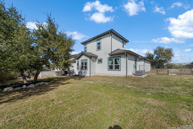 rear view of property featuring metal roof, central AC, fence, a lawn, and a standing seam roof