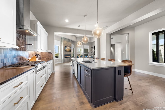 kitchen featuring stainless steel gas cooktop, a large fireplace, a sink, backsplash, and wall chimney exhaust hood