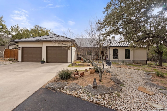 view of front of house featuring metal roof, a garage, driveway, stucco siding, and a standing seam roof