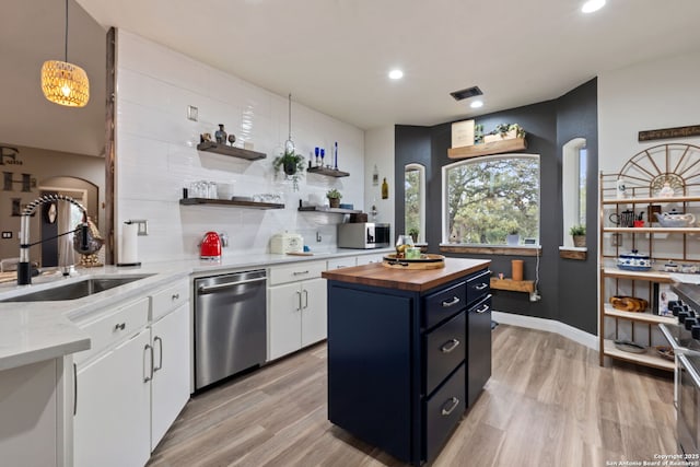 kitchen with decorative backsplash, butcher block countertops, appliances with stainless steel finishes, white cabinetry, and a sink