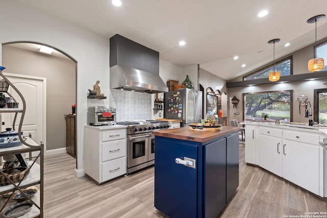 kitchen with island range hood, white cabinets, appliances with stainless steel finishes, blue cabinetry, and wooden counters