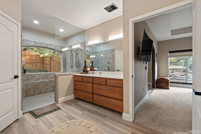 bathroom featuring wood finished floors, vanity, and walk in shower