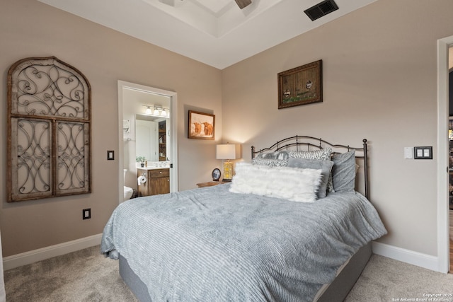 carpeted bedroom featuring connected bathroom, visible vents, and baseboards