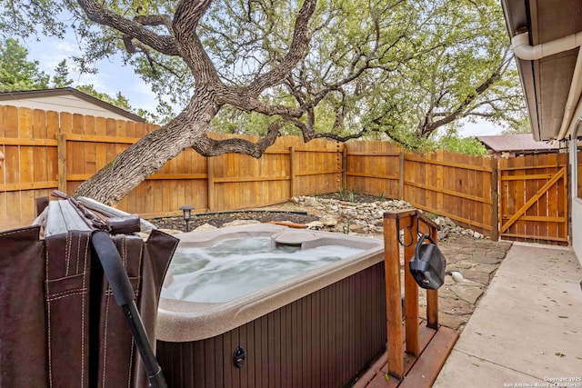 view of patio featuring fence private yard, a hot tub, and a gate