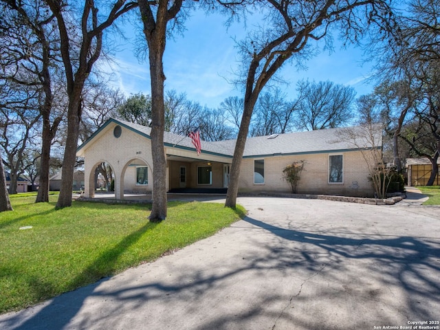 view of front of property with driveway, a front yard, and brick siding