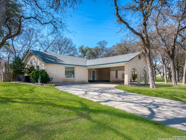 single story home with concrete driveway, brick siding, a front lawn, and a shingled roof