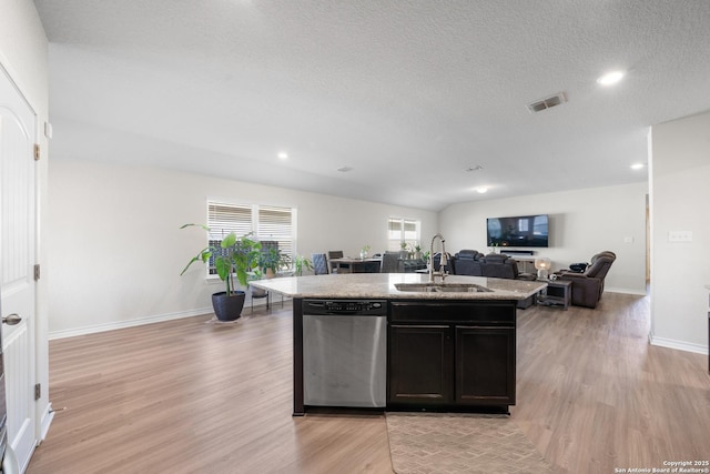 kitchen with light wood finished floors, visible vents, dishwasher, open floor plan, and a sink