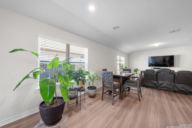 dining room featuring visible vents, vaulted ceiling, light wood-style flooring, and baseboards