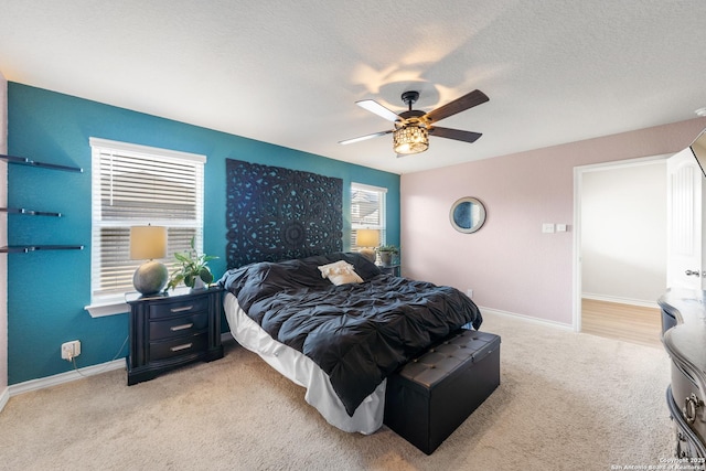 bedroom featuring light carpet, ceiling fan, a textured ceiling, and baseboards