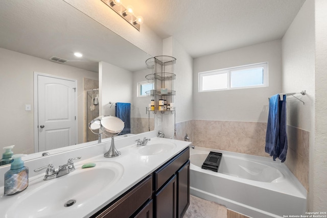 bathroom with visible vents, a sink, a garden tub, and double vanity