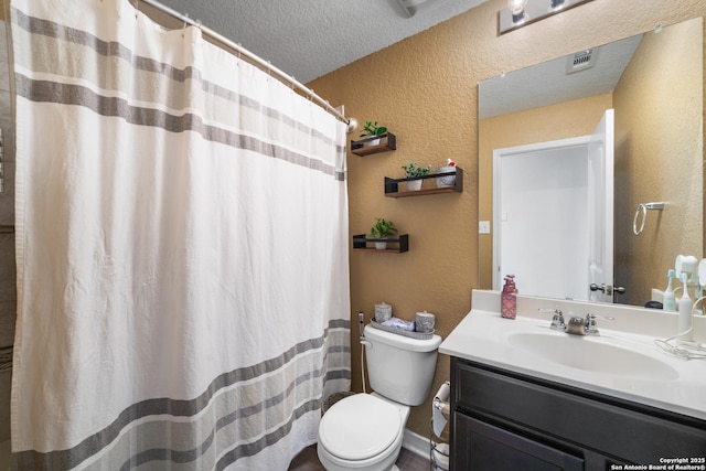 full bathroom with toilet, vanity, a textured ceiling, and a textured wall