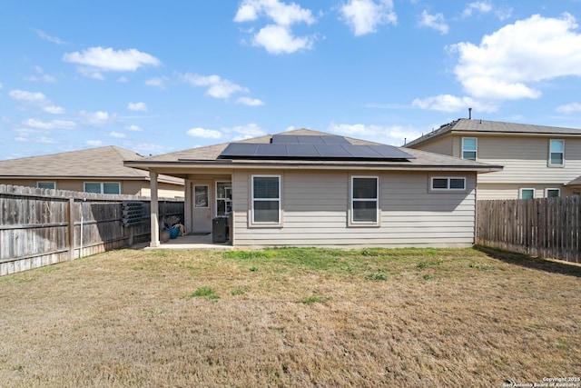 back of house featuring solar panels, a yard, a patio area, and a fenced backyard