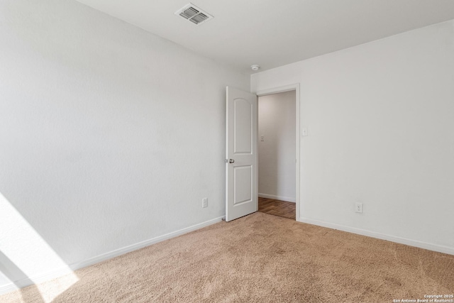 empty room with light carpet, visible vents, and baseboards