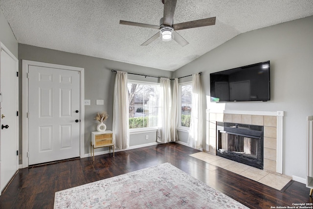 unfurnished living room featuring ceiling fan, wood finished floors, vaulted ceiling, a textured ceiling, and a fireplace