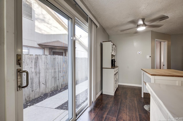 entryway with dark wood-style floors, visible vents, ceiling fan, a textured ceiling, and baseboards